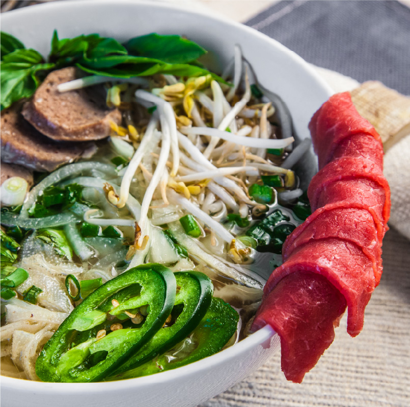 photo of pho with slices of beef on the side and fresh vegetables and sprouts on top